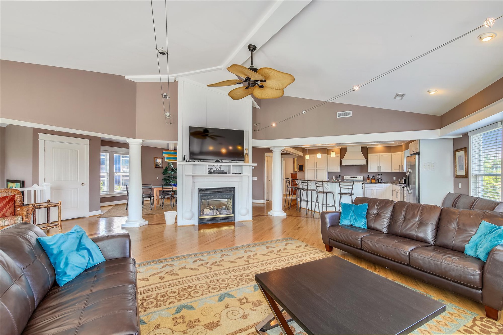 Relax in this spacious living room featuring leather sofas, a cozy fireplace, and open flow to the kitchen—ideal for unwinding after your adventures or gathering together.
