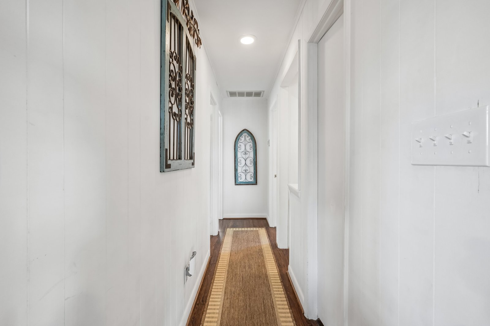 Bright hallway with warm hardwood floors and charming decorative touches guides you to your private spaces.