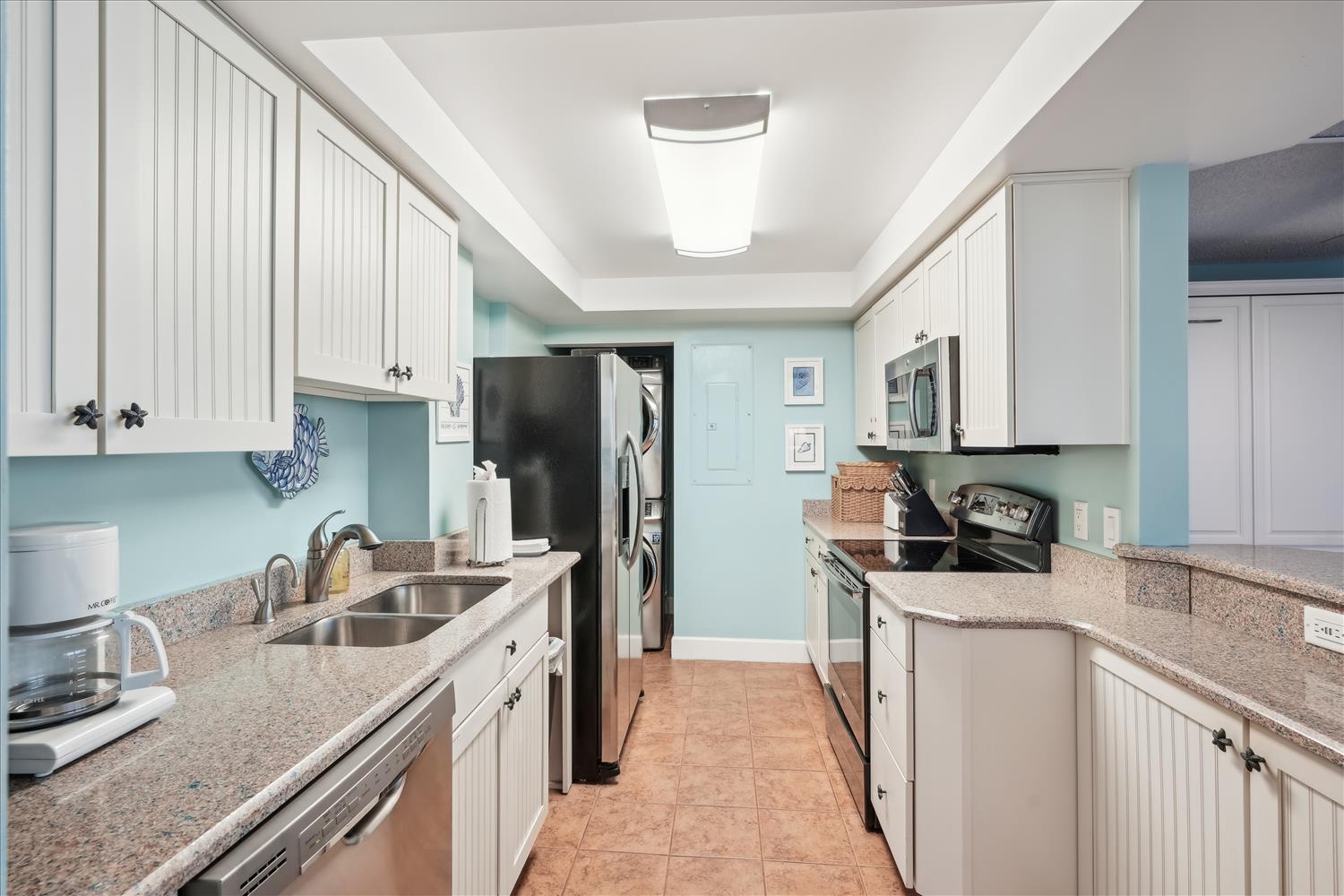 This spacious galley-style kitchen features modern stainless appliances, granite countertops, and crisp white cabinetry to make meal prep a breeze during your stay.