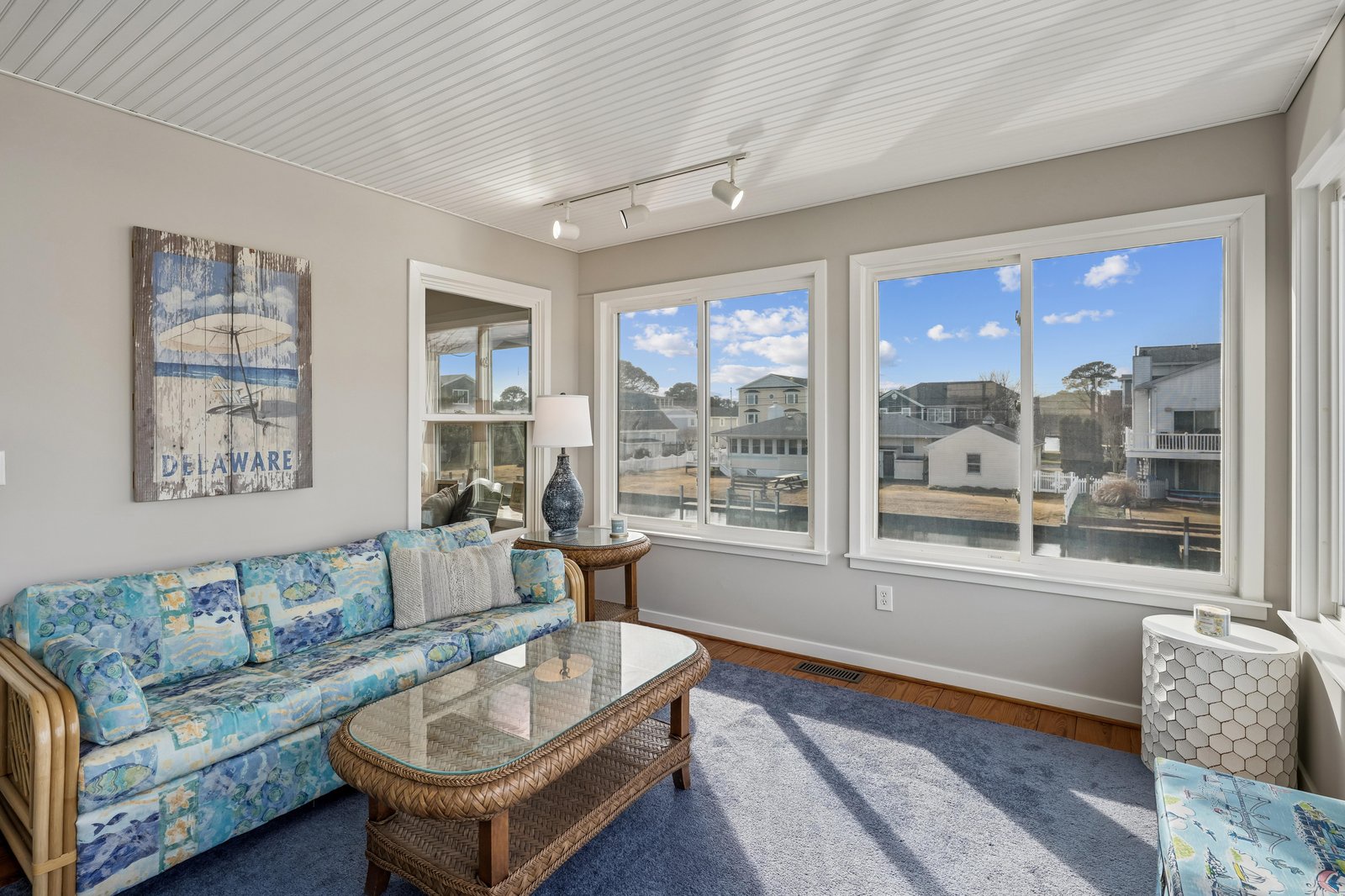 Relax in your bright, coastal-style living room with soft blue hues, comfy seating, and large windows inviting natural light and waterfront views throughout the day.