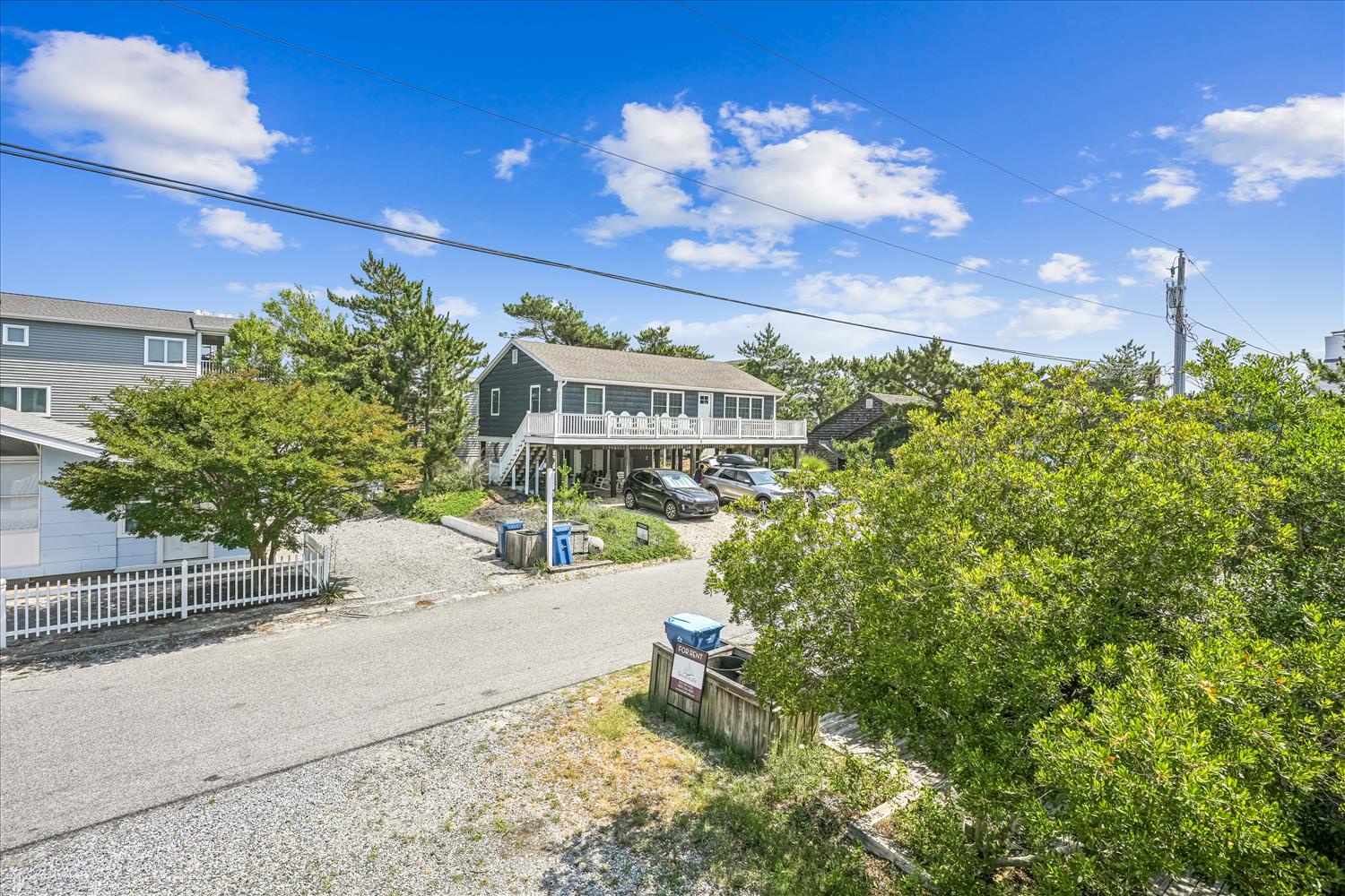 Elevated coastal property nestled among lush greenery in a quiet residential neighborhood, with convenient parking and easy beach access nearby.