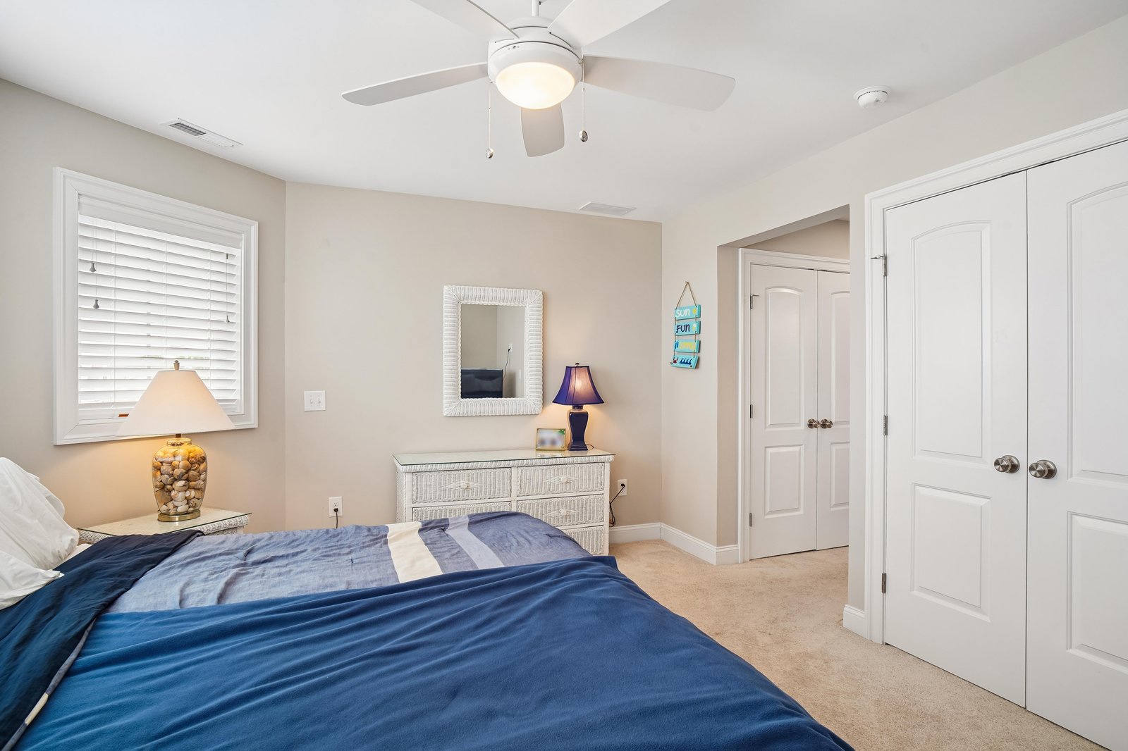 Drift off to sleep under the gentle breeze of the ceiling fan in this peaceful bedroom. Soft lighting and coastal touches create a serene retreat for your vacation.