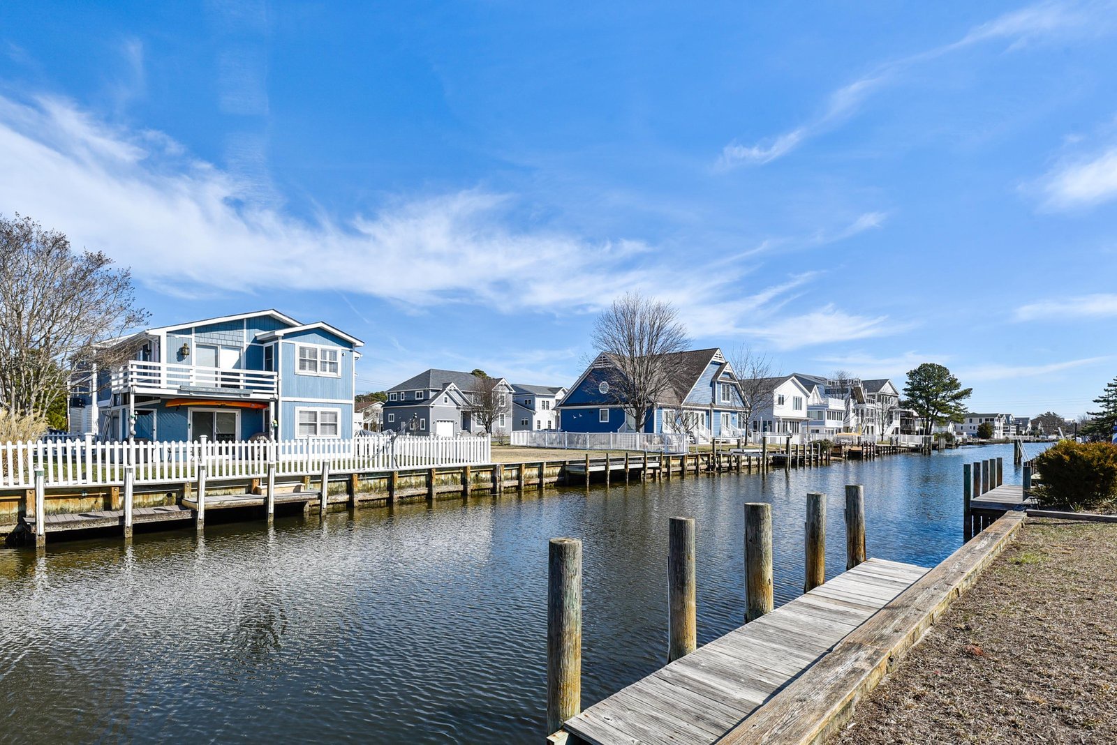 A charming waterfront neighborhood features private docks along a peaceful canal, with inviting beach homes creating a relaxed coastal community atmosphere.