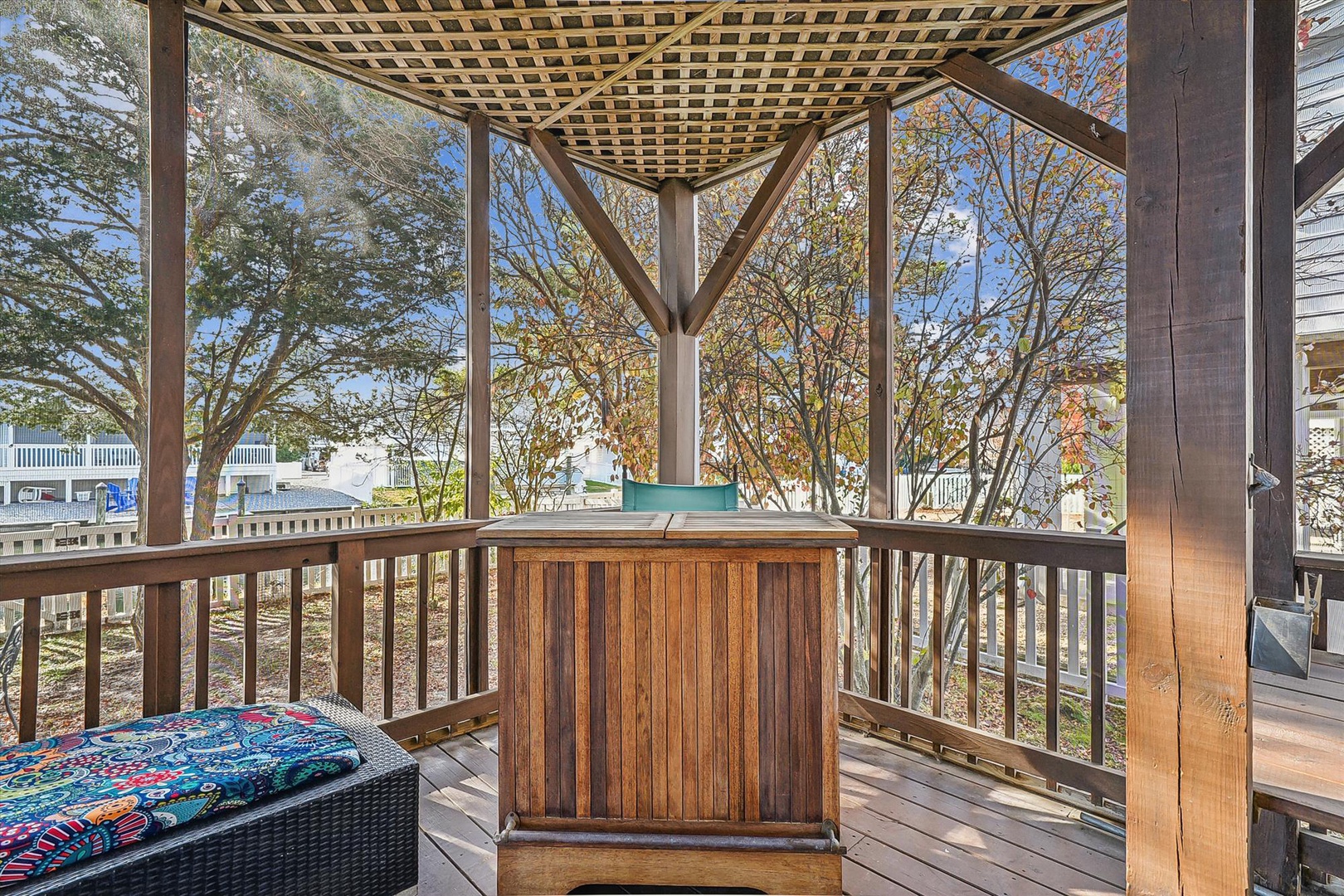 A peaceful covered deck with a hot tub and scenic tree-lined views, perfect for autumn relaxation under natural shade and open skies.