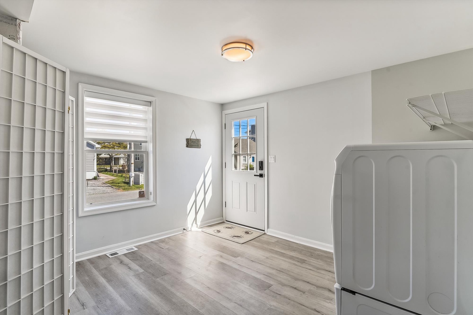 A bright, functional laundry area features modern appliances and gleaming floors, with natural light streaming through the window to make chores feel easier and more pleasant.