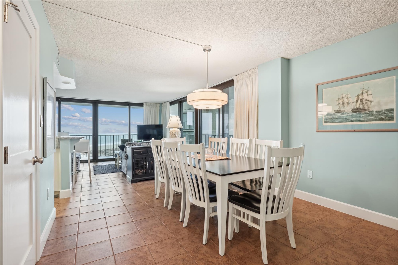 Gather around your elegant dining table with ocean views streaming through floor-to-ceiling windows, creating the perfect backdrop for memorable meals together.