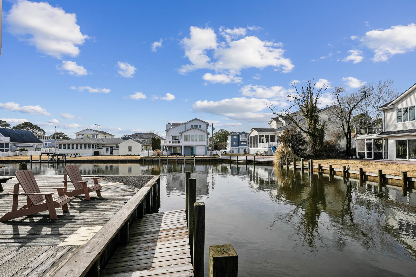 A peaceful waterfront community with private docks and boat slips along a calm canal. Charming homes line the waterway beneath open skies.