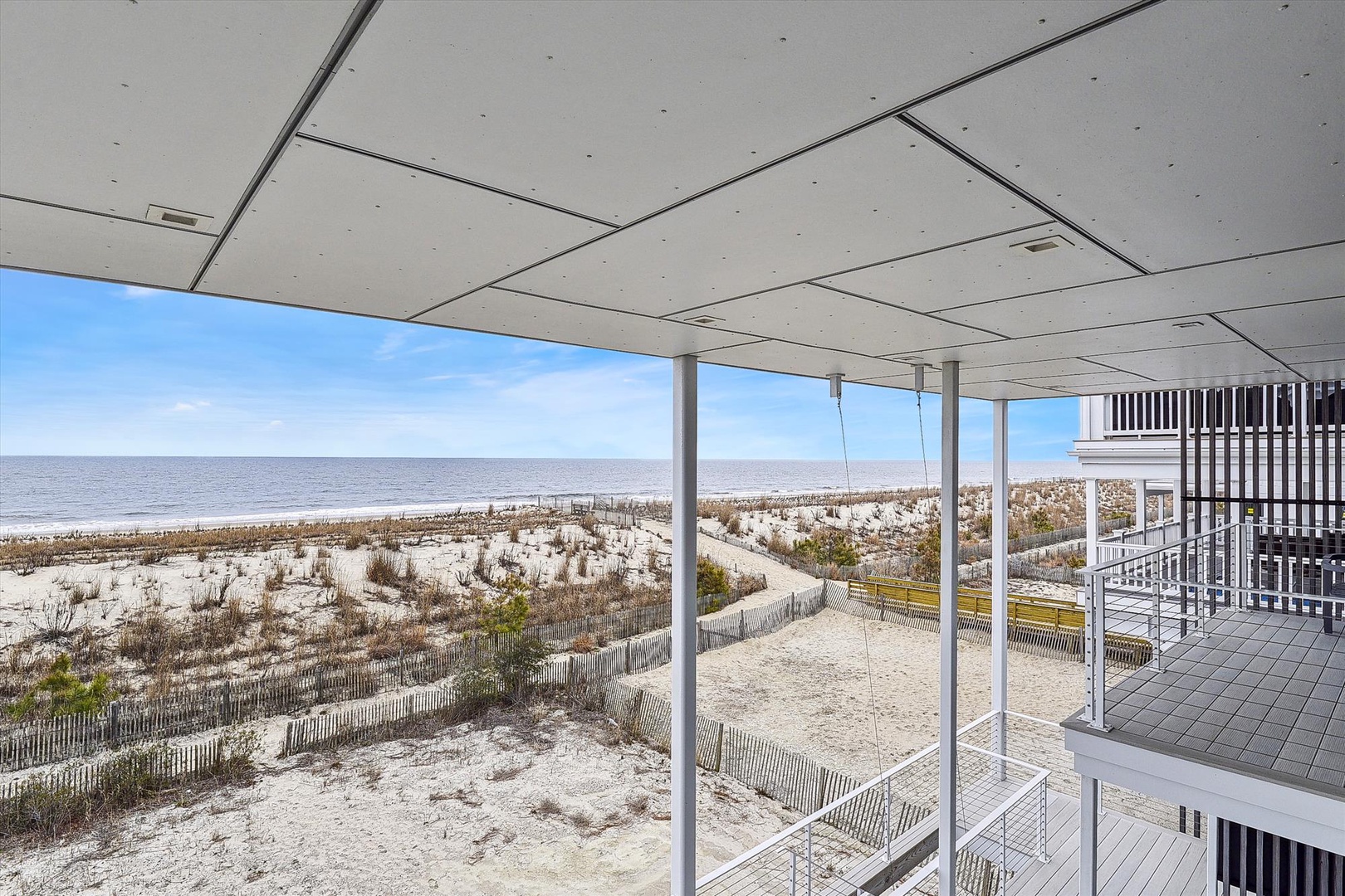 This modern beachfront property offers direct views of sandy shores, gentle dunes, and the expansive sea beyond, creating a serene coastal atmosphere for your entire stay.