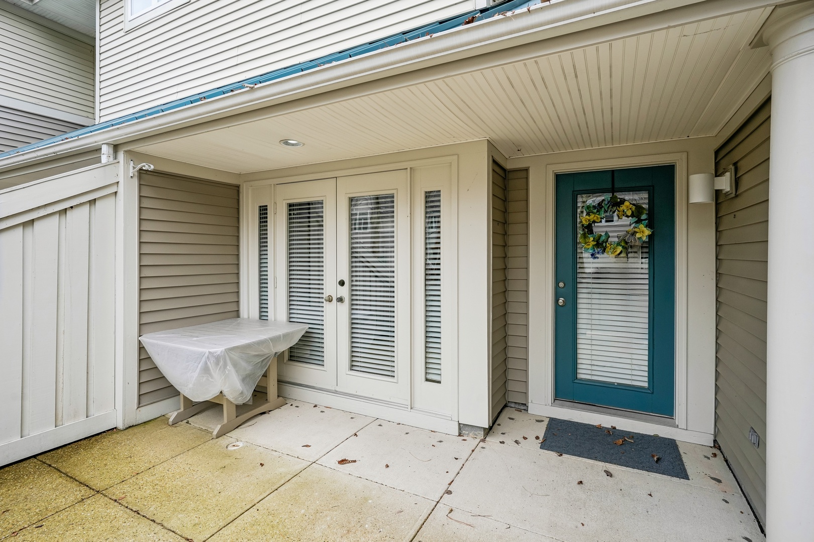 Covered front entrance with teal door featuring seasonal wreath, offering a warm welcome to your home away from home.