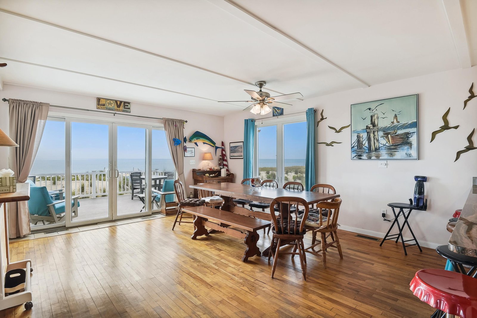 Gather around the rustic dining table where ocean breezes drift through open doors and coastal views frame every meal. The warm wood floors and nautical charm make this your home away from home.