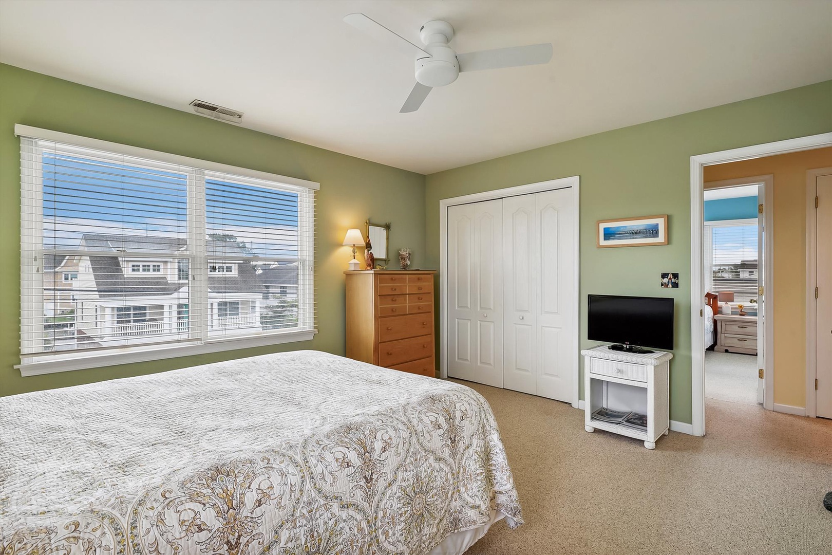 Drift off in your tranquil retreat with soft green walls, plush bedding, and calming neighborhood views streaming through bright windows. Your ceiling fan ensures perfect comfort.