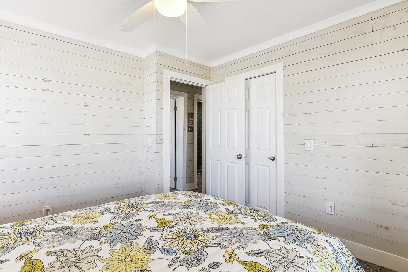 Your cozy bedroom features charming shiplap walls and a ceiling fan with light. Wake up refreshed in this bright, comfortable space designed for peaceful sleep.