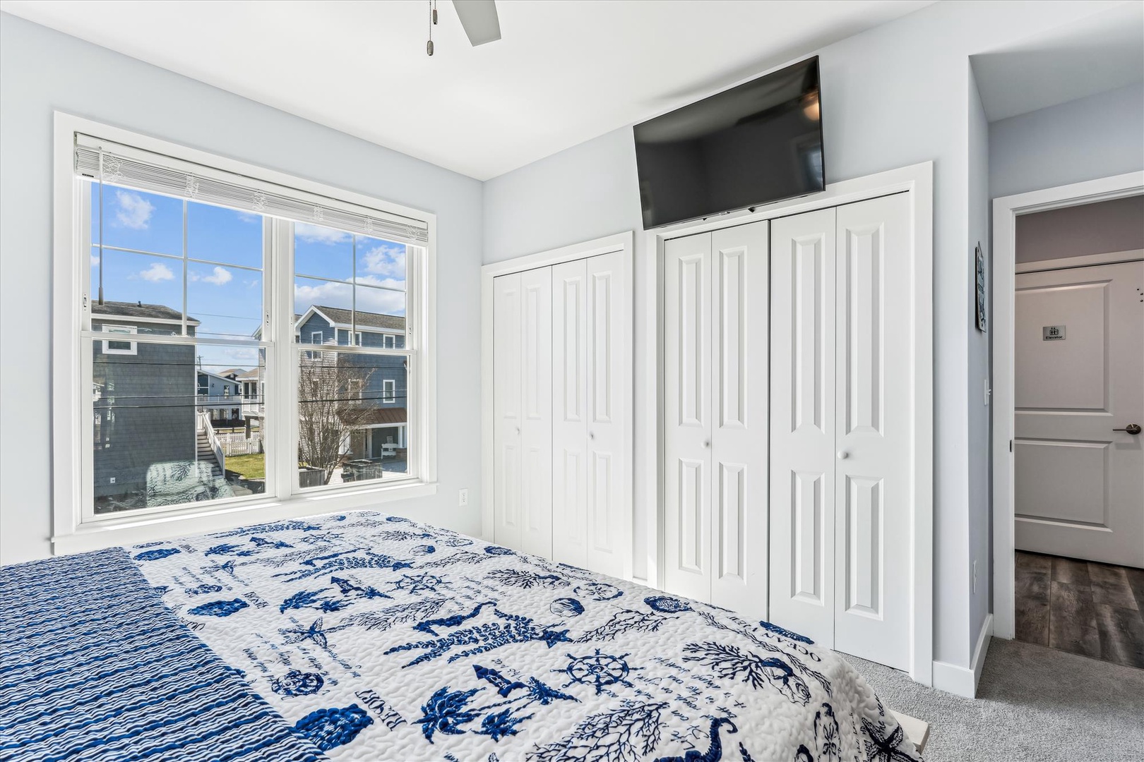 Bright coastal bedroom with nautical-themed linens, flat-screen TV, and ample closet space for your vacation wardrobe.