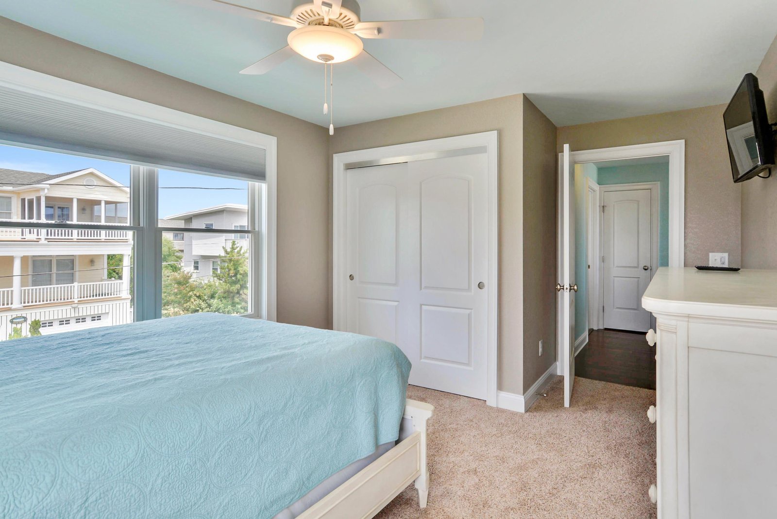 Your tranquil bedroom retreat features soothing coastal tones, soft carpet underfoot, and a ceiling fan to keep you comfortable. Through the window, catch a glimpse of the surrounding neighborhood.