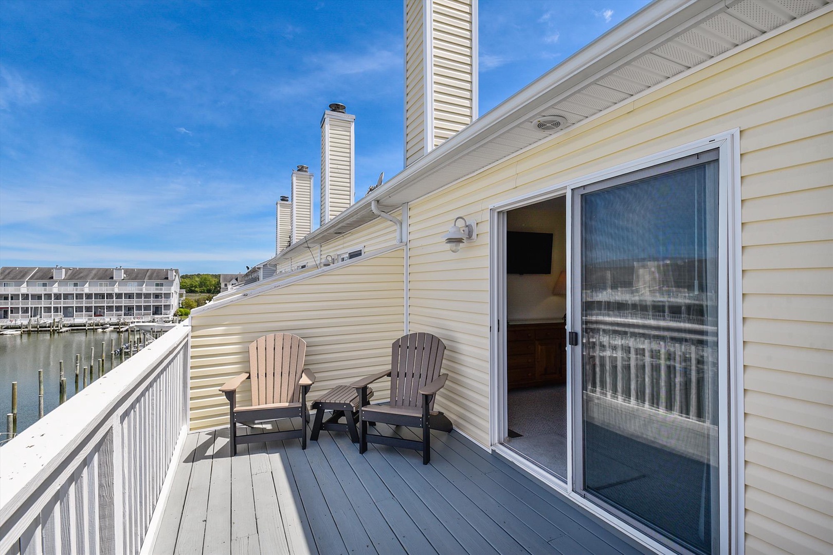 The waterfront deck overlooks calm marina waters, where two Adirondack chairs invite peaceful mornings with your coffee. A private space to watch boats drift by.