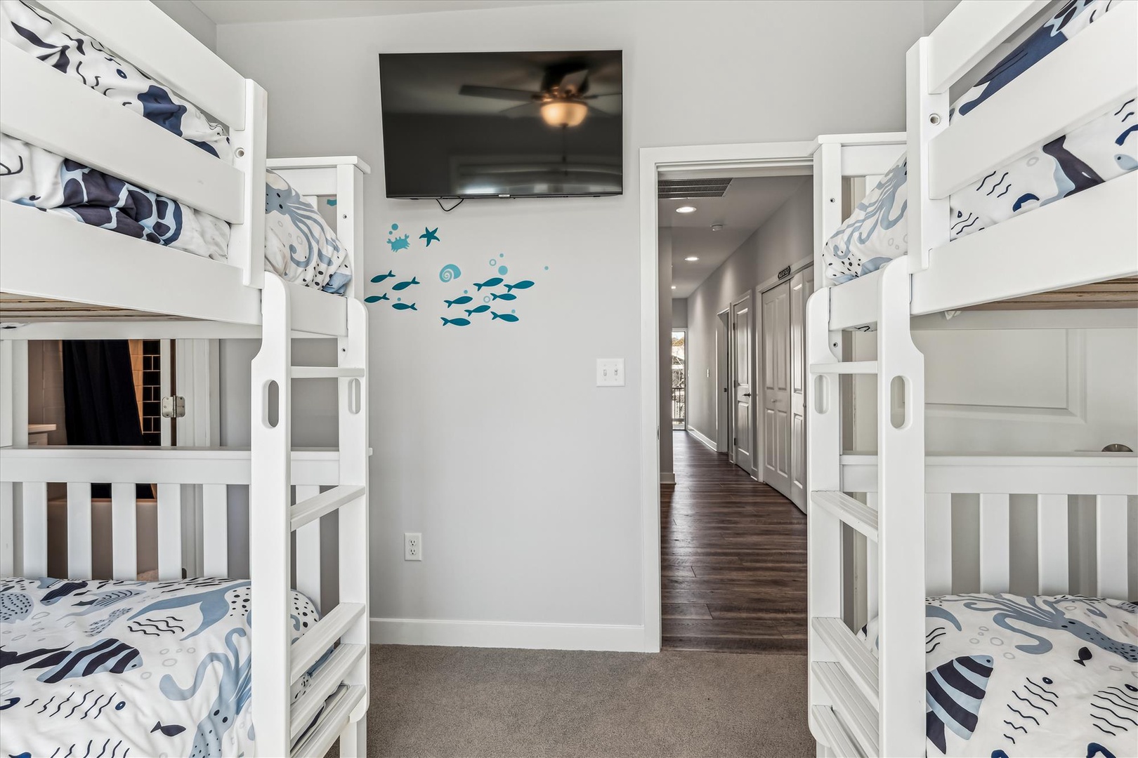 Cozy bunk room designed for the whole crew, with ocean-themed bedding, a mounted TV, and plenty of sleeping space for memorable family stays.