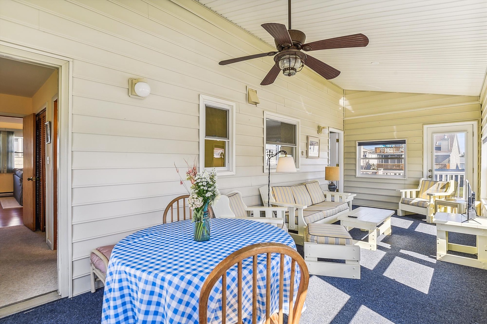Picture yourself unwinding in this breezy, sunlit porch with comfortable seating, a charming dining spot, and gentle ceiling fan—your perfect retreat after a day of exploring.