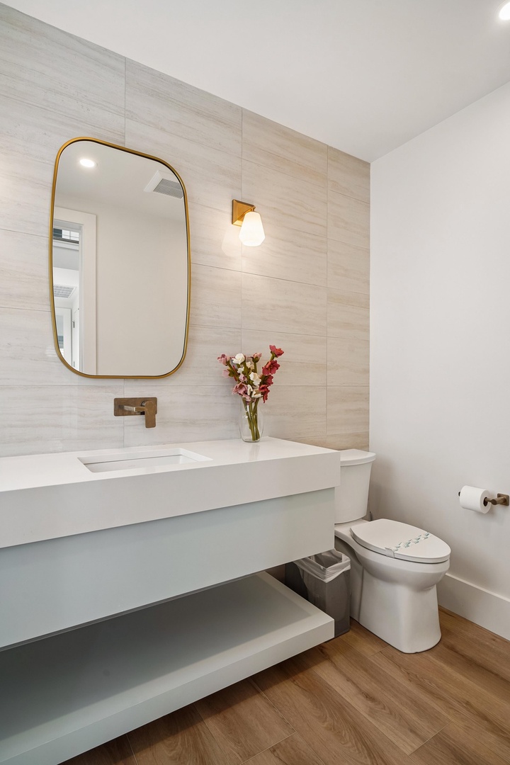 Freshen up in your modern bathroom with elegant brass fixtures, warm wood-grain tiles, and a sleek floating vanity designed for your comfort.