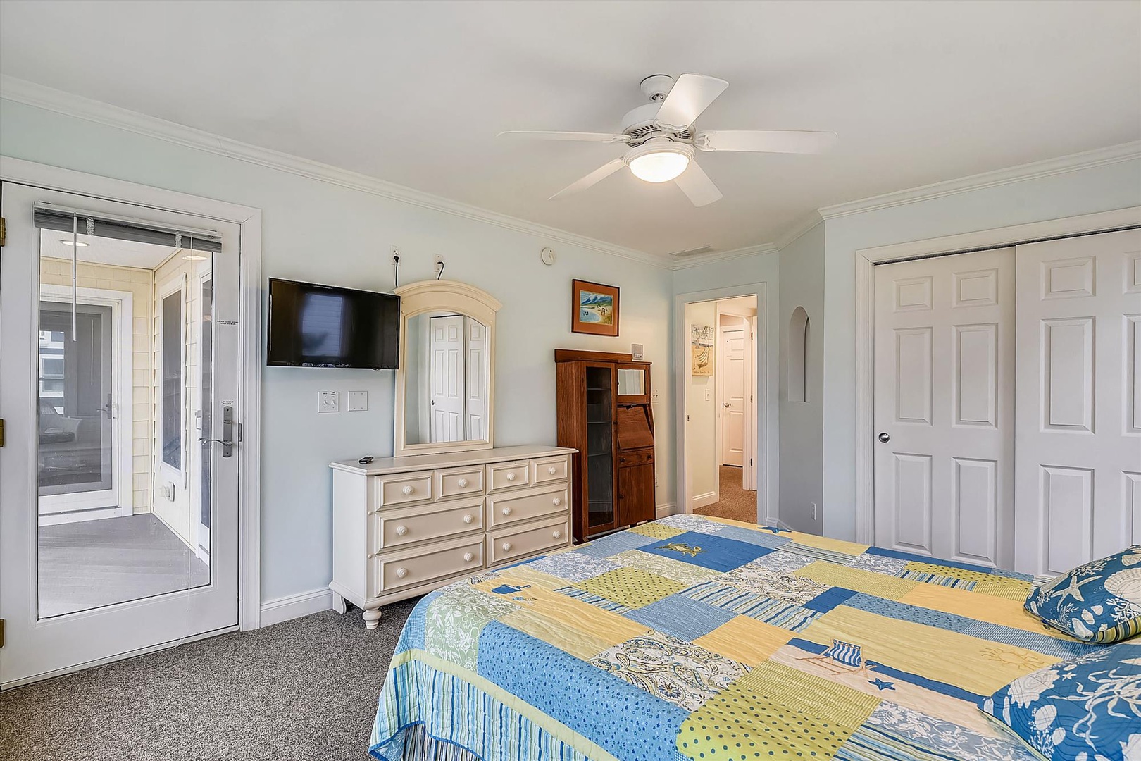Your bright coastal bedroom welcomes you with soft blues and yellows, a ceiling fan to keep you comfortable, and French doors opening to the outdoors—perfectly relaxing after a day of adventure.