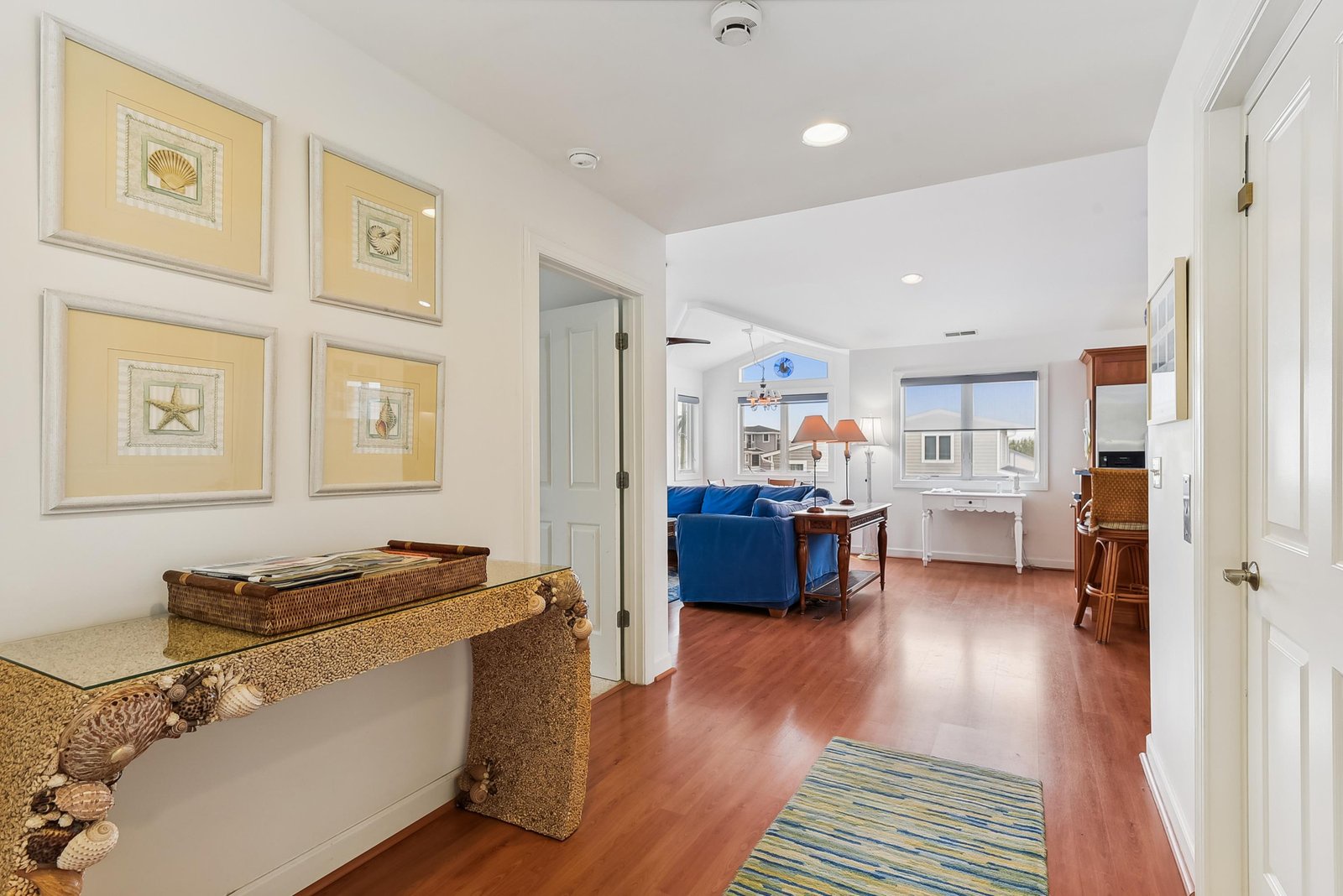 Step into your coastal escape where warm wood floors flow from room to room, inviting you to settle into comfortable living spaces that effortlessly blend beach charm with home-like ease.