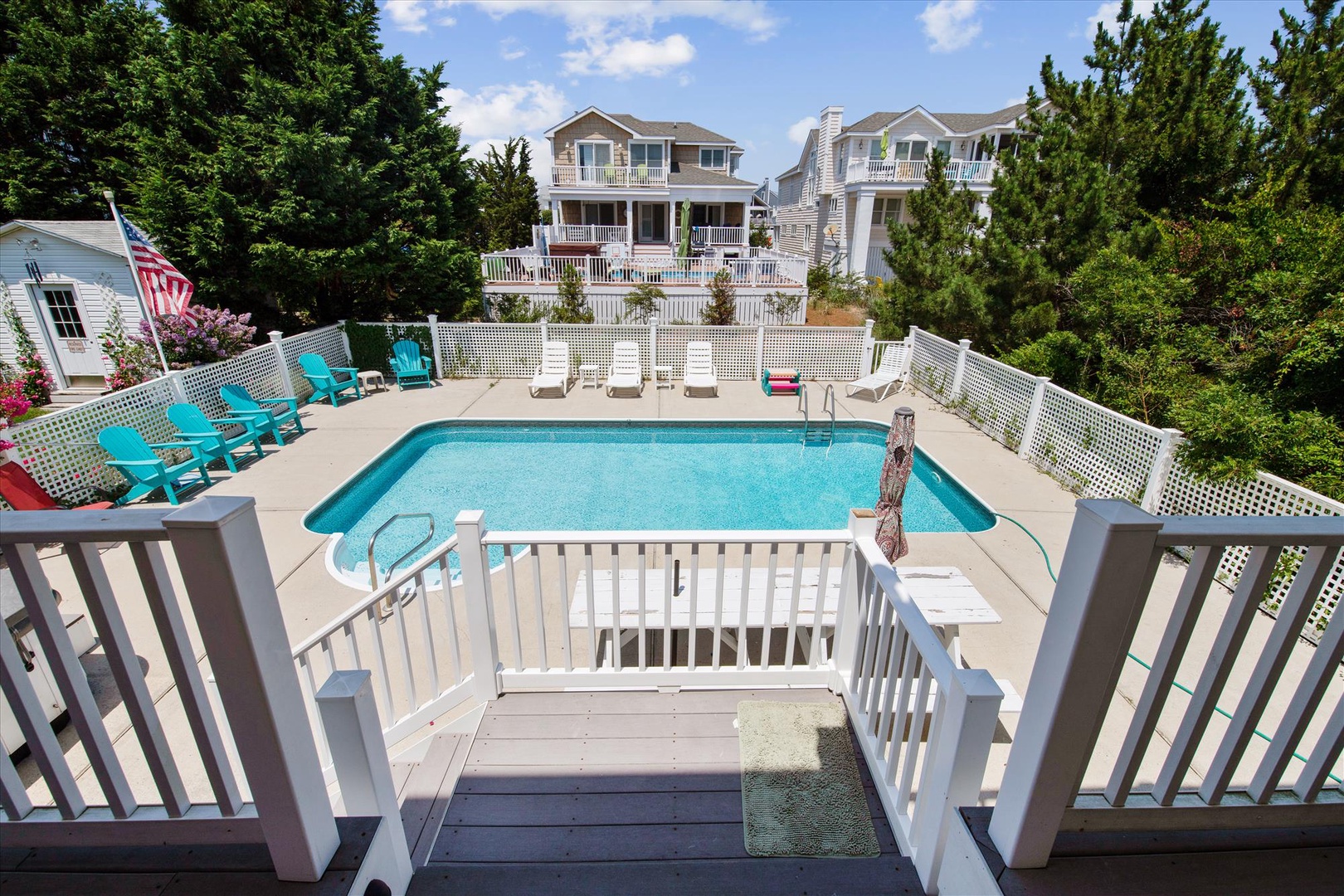 Spacious private pool deck with bright turquoise water, colorful lounge chairs, and sunny ambiance. Perfect for relaxing, swimming, and soaking up coastal vibes during your stay.