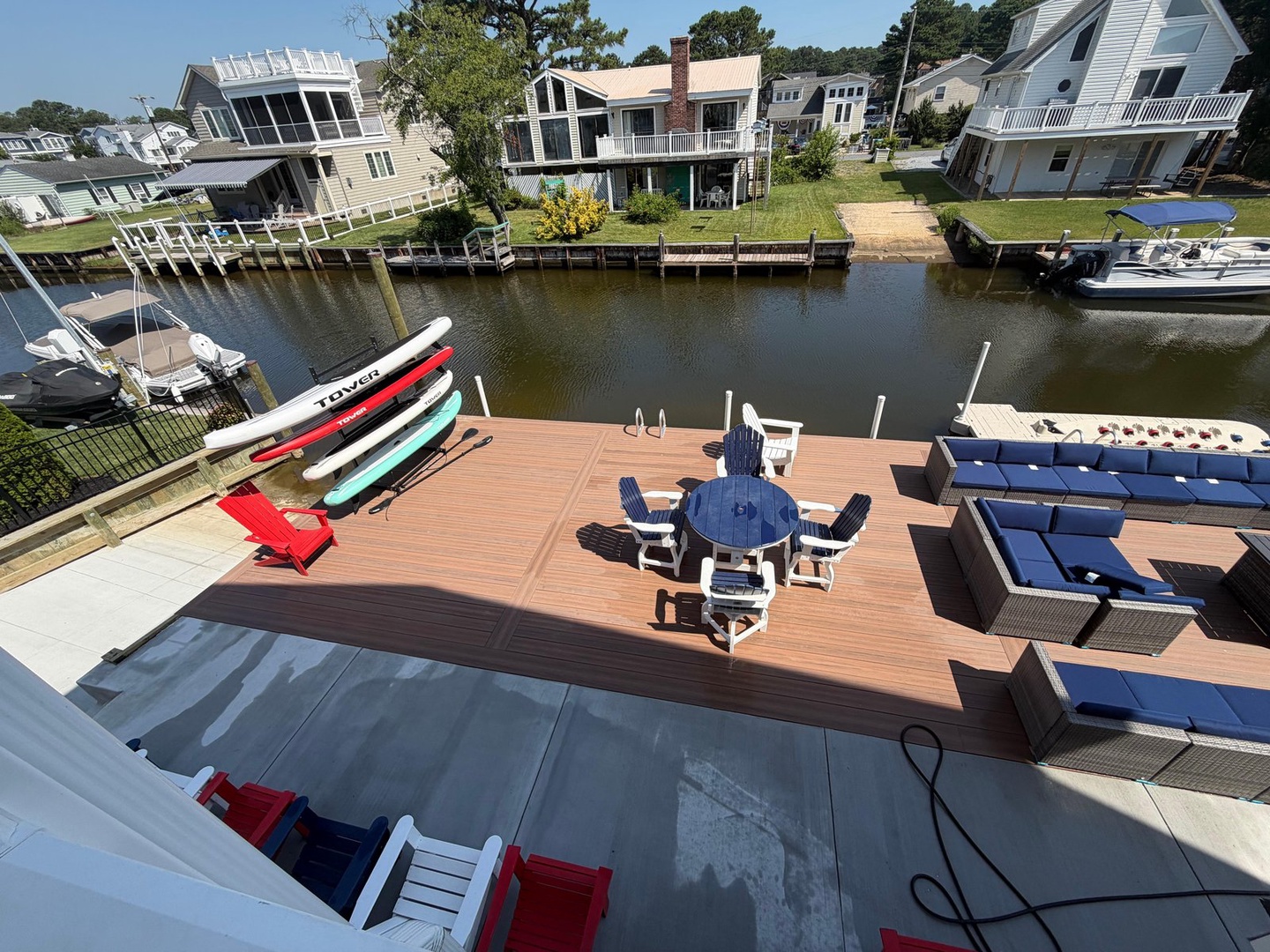Waterfront deck with dining, lounge seating, and paddleboards along a private canal—your own slice of summer paradise.