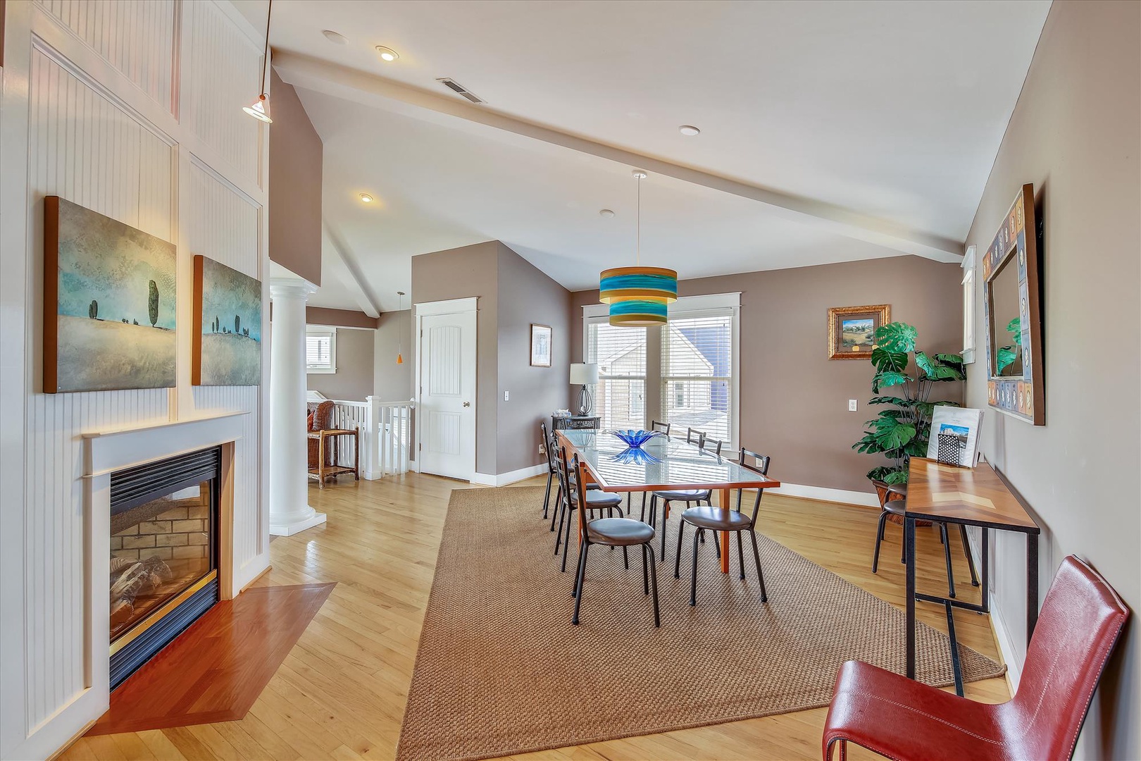 Your open dining space features soaring vaulted ceilings, coastal-inspired decor, and natural light flooding through large windows. The cozy fireplace sets the perfect ambiance for memorable meals together.