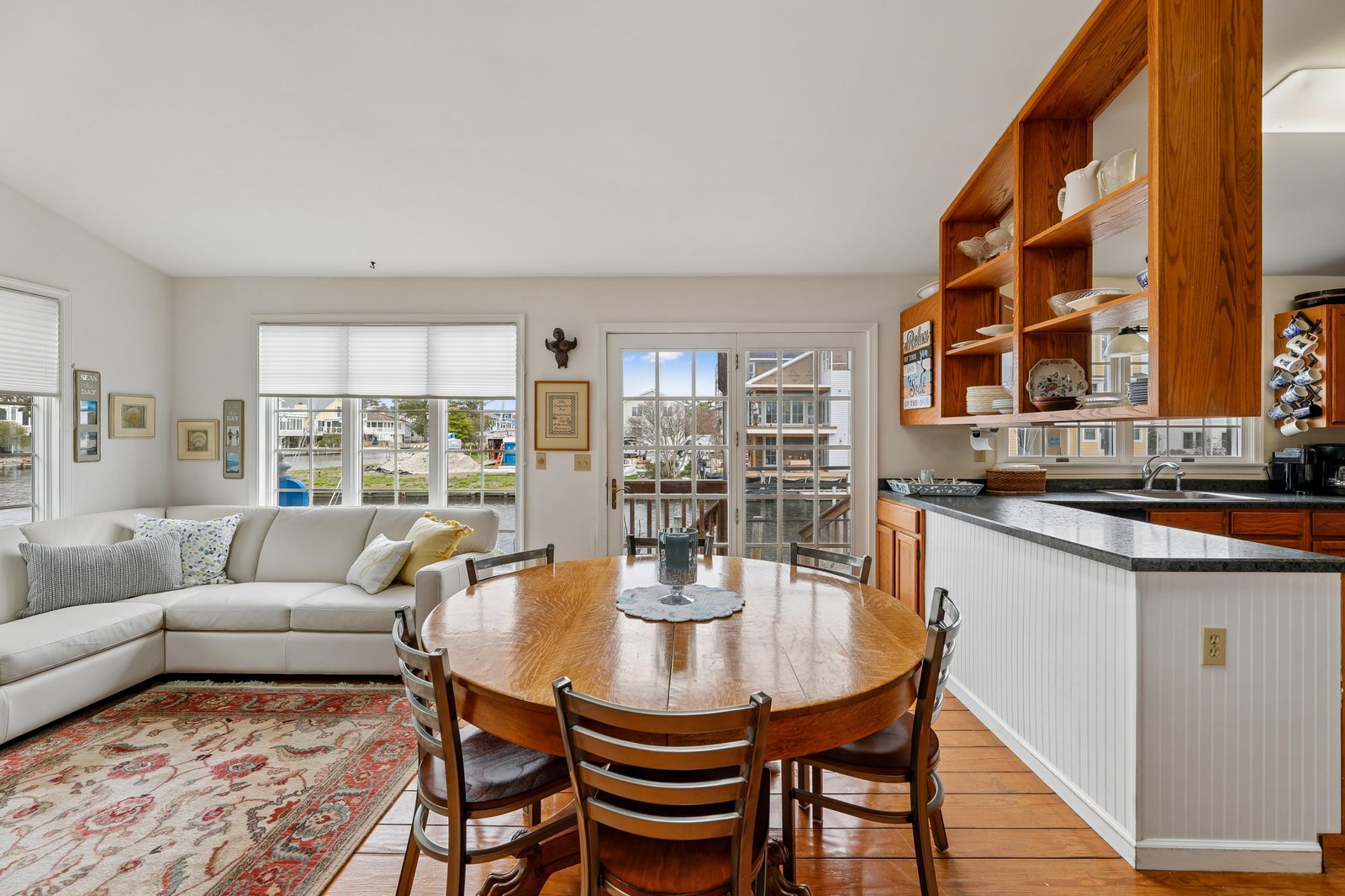 Step into your open-concept living space where warm wood tones meet coastal charm. French doors frame marina views, inviting you to your private deck. Gather around the dining table after a day exploring, or relax on the sofa with a view.