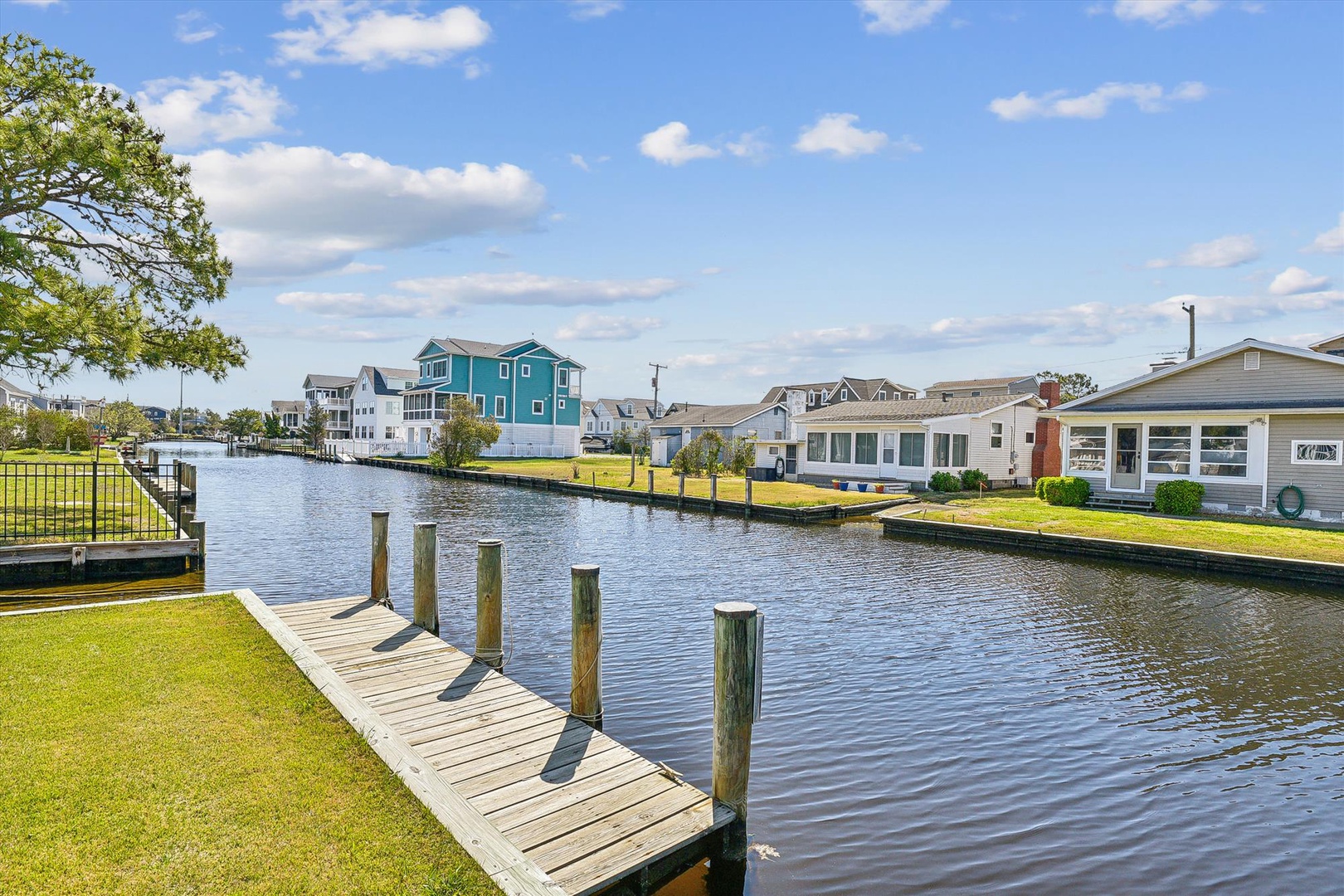 Waterfront rental community featuring private boat docks along a peaceful canal, surrounded by manicured lawns and a variety of well-maintained vacation homes under clear skies.