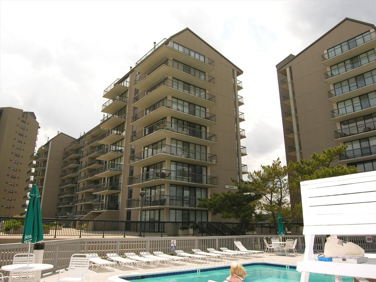 Multi-story condominium buildings situated near an outdoor pool area, part of a larger vacation rental community.