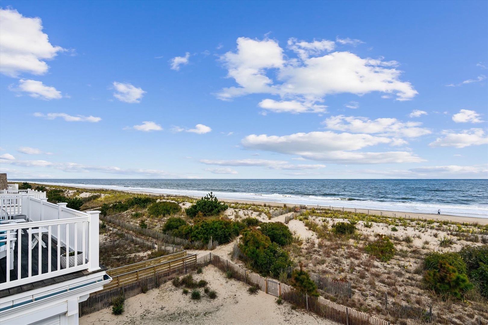 Expansive beachfront property with pristine sandy shores and direct ocean access, featuring natural dune vegetation and gentle rolling waves under blue skies.