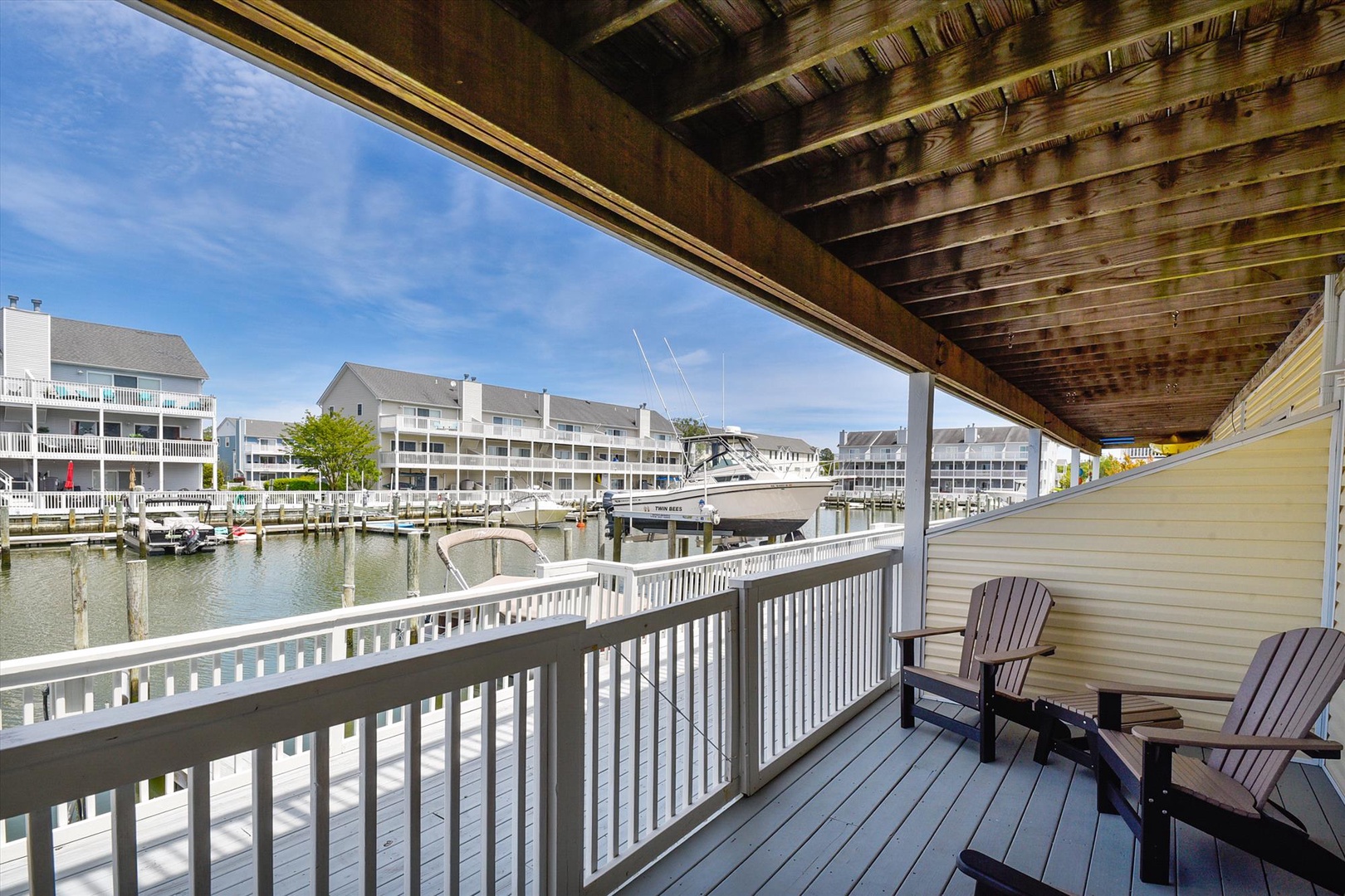 Step out onto your private covered balcony and take in peaceful waterfront views with boats gently docked nearby, where sunlight dances on the water and invites you to relax in comfort.
