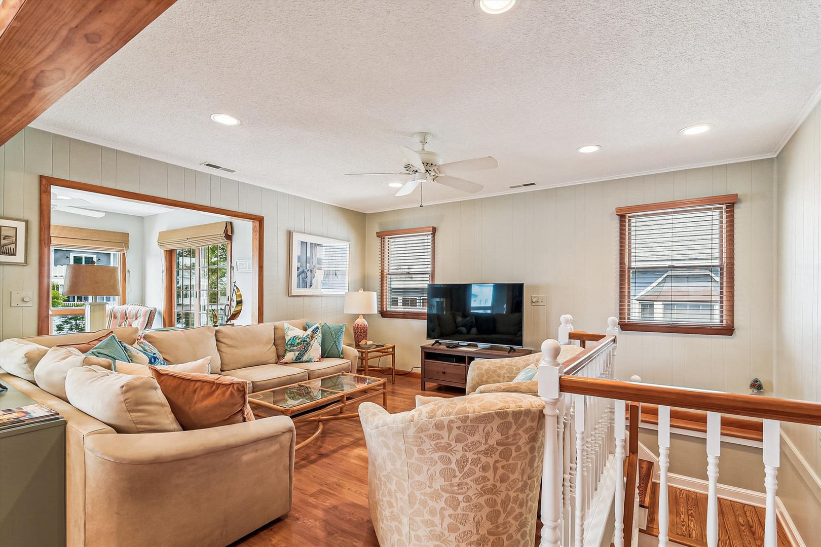 Sink into plush seating and enjoy your favorite shows in this welcoming upstairs living room, where coastal charm meets comfort with warm wood accents and natural light streaming through the windows.