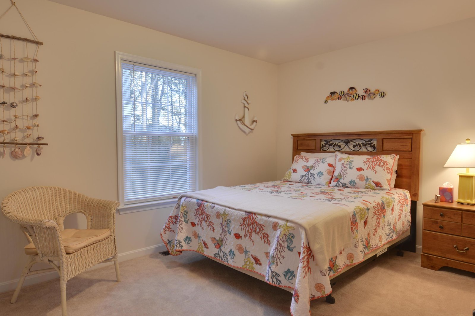 Your coastal-themed bedroom invites restful nights with a comfortable queen bed, charming sea life accents, and soft natural light filtering through the window.