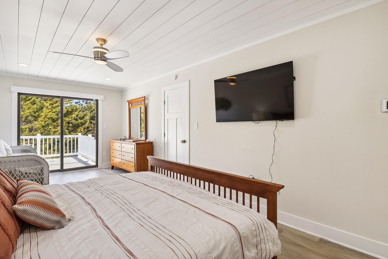 Wake up to tree-filled views through your private balcony doors, where natural light brightens warm wood tones and a ceiling fan keeps you comfortable year-round.