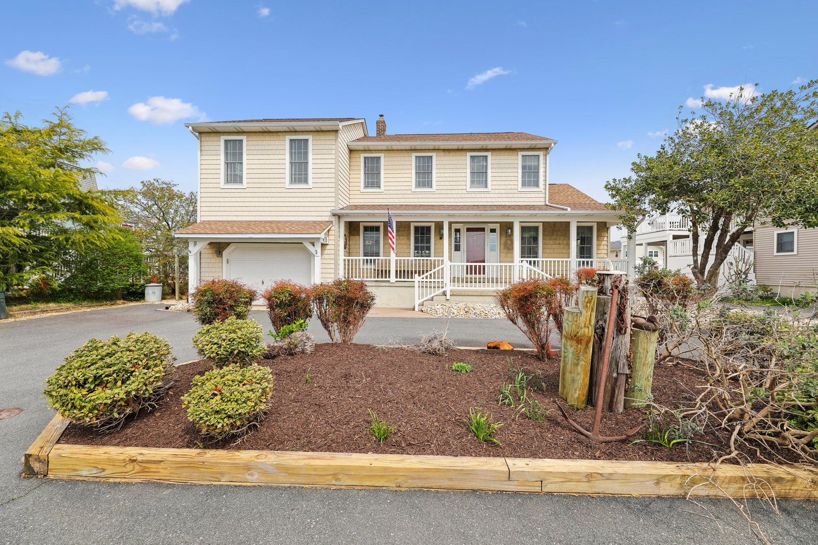 A welcoming two-story property with a covered front porch and garage, set in a landscaped neighborhood surrounded by mature trees.