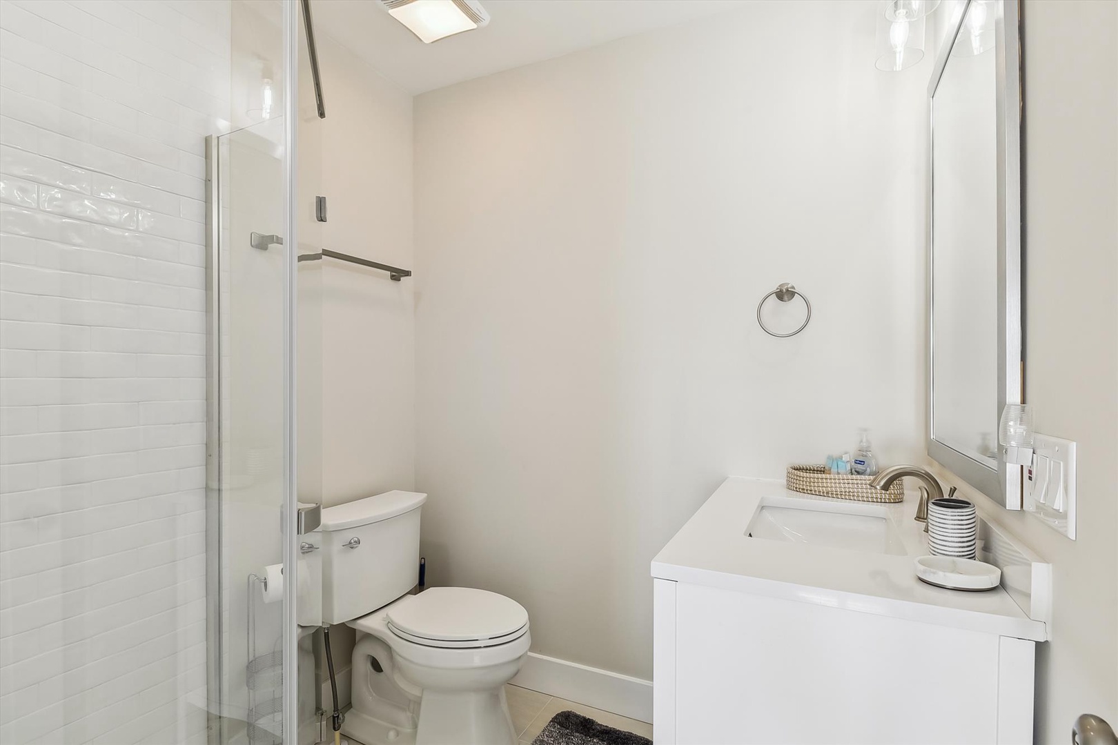 Step into your bright, modern bathroom with a spacious walk-in shower, clean white vanity, and skylight that fills the space with natural light for a refreshing start to your day.