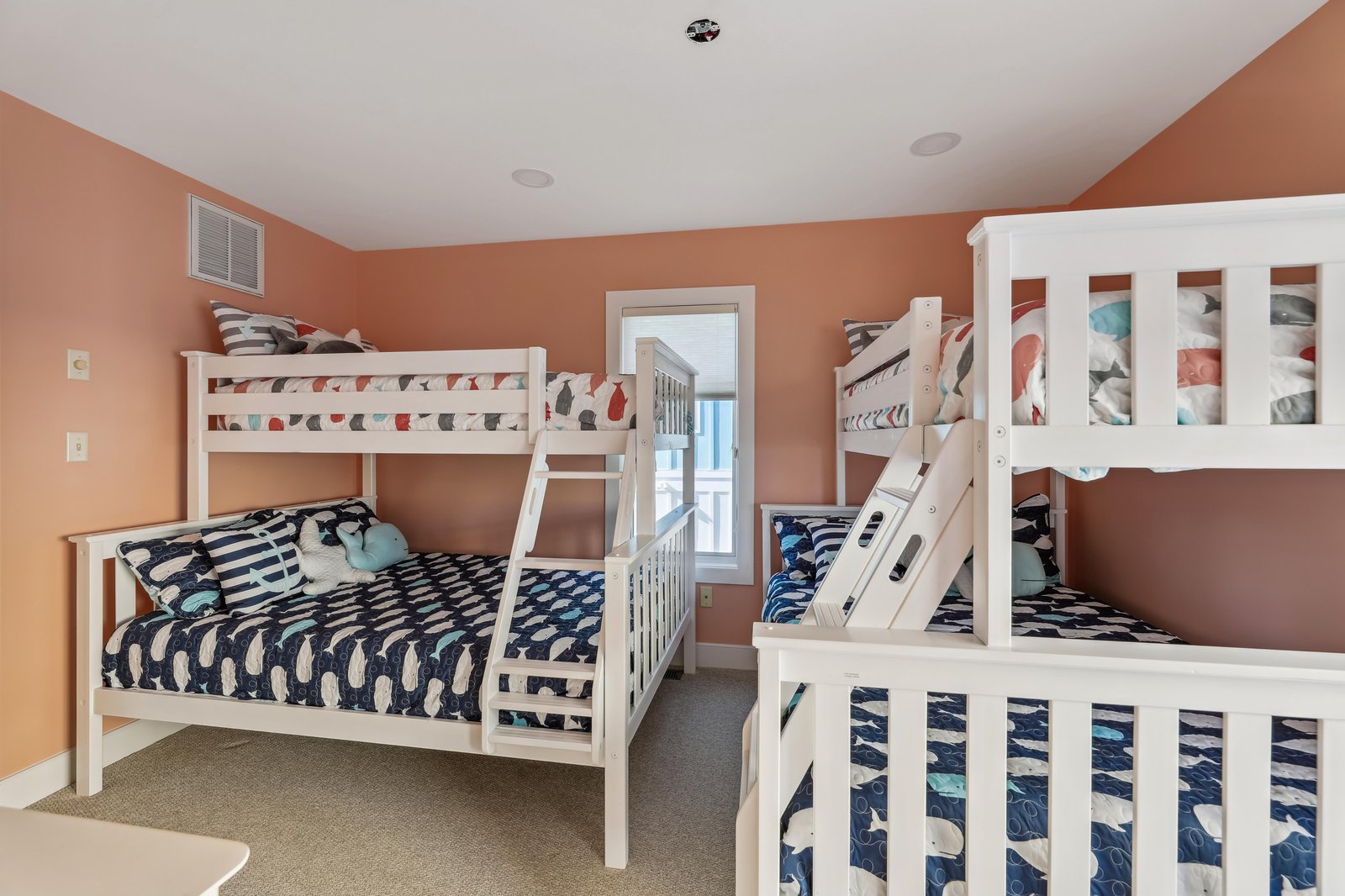 Gather your crew in this cheerful bunk room, where soft coral walls and nautical bedding create a playful retreat perfect for sweet dreams and morning giggles.