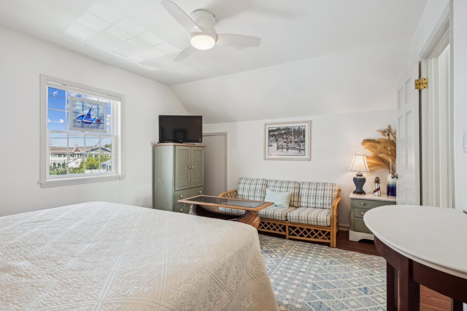 Step into your peaceful bedroom retreat featuring a plush queen bed, coastal decor, and a ceiling fan to keep you comfortable. Sink into the cozy loveseat and enjoy your favorite shows after a day of beach adventures.