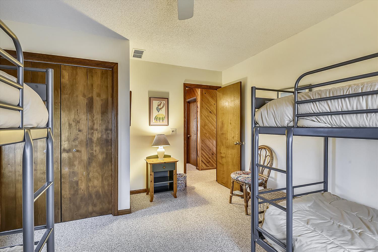 Your cozy bunk room waits with space for the whole crew to rest after a day of adventure. Soft carpets, warm wood tones, and a nightstand lamp create a peaceful retreat for easy mornings and restful nights.