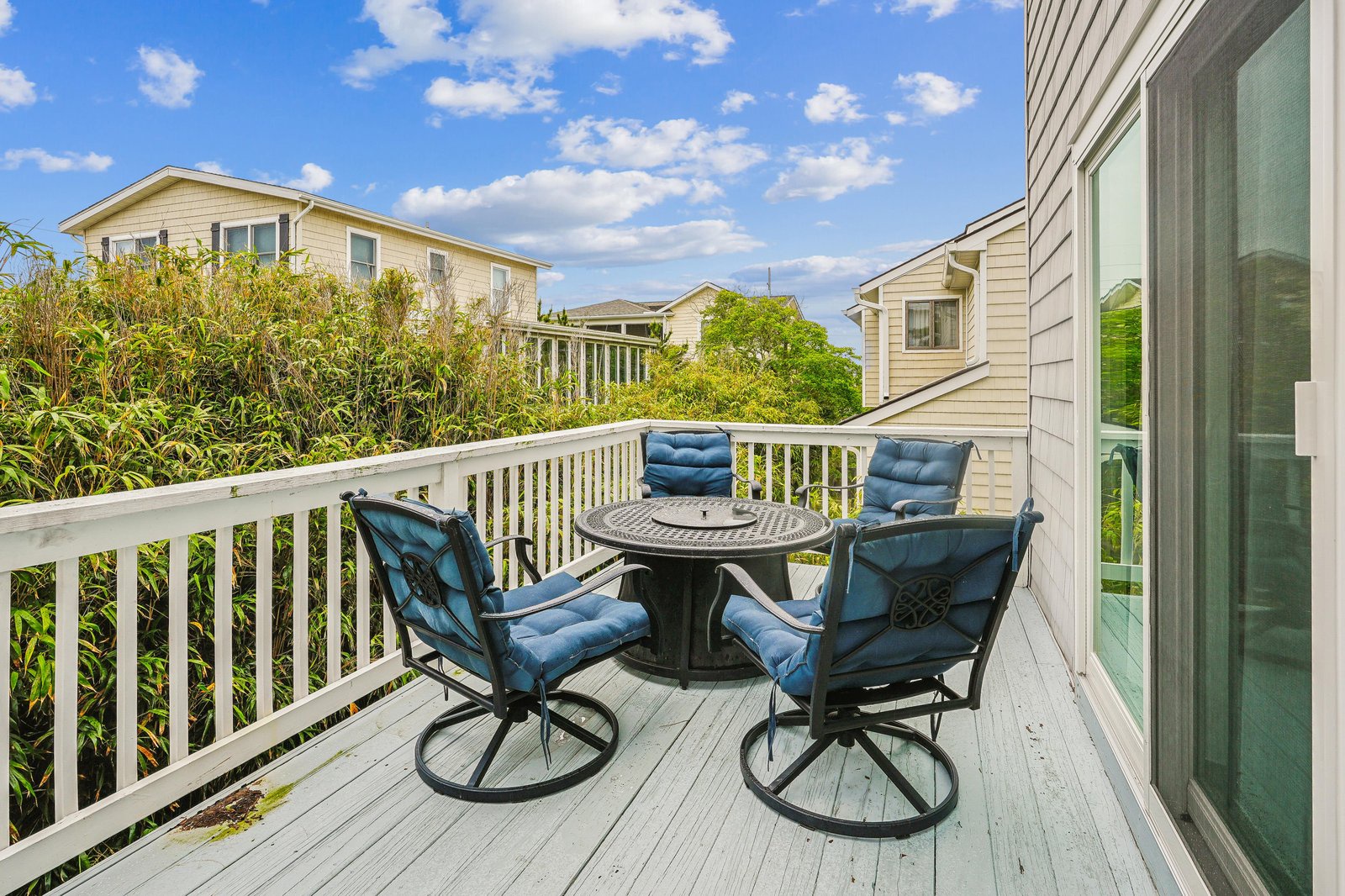 Your private balcony invites you to unwind under a bright coastal sky, with comfortable cushioned seating and fresh breezes. Perfect for morning coffee or evening conversation, it's your peaceful spot to soak in the neighborhood charm.