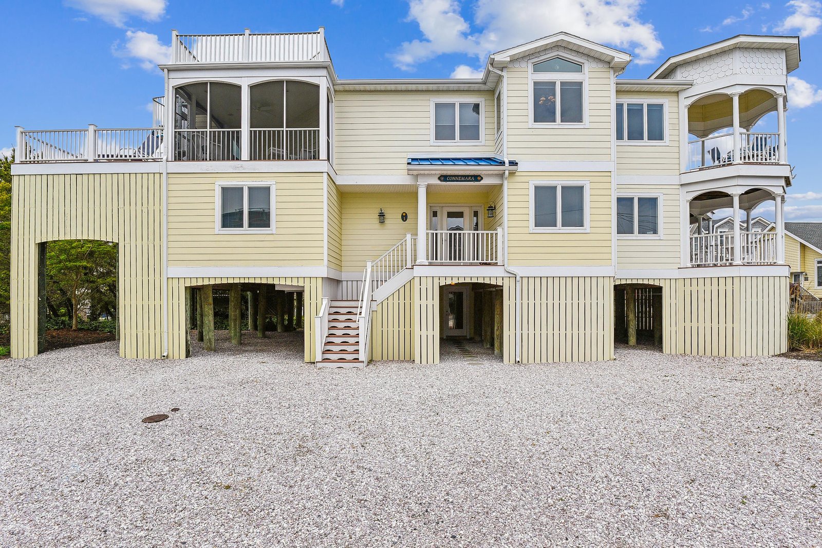 A multi-level coastal home elevated on stilts features multiple balconies and covered parking, perfectly designed for easy beach access and coastal living.