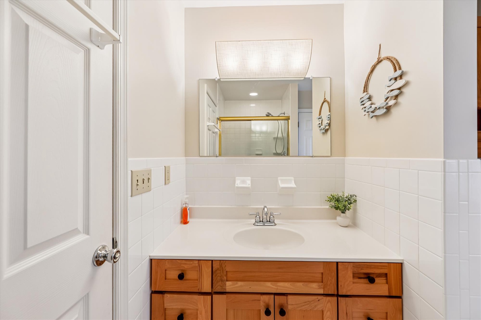 Step into your bright, spotless bathroom with charming coastal touches, natural wood vanity, and fresh white tile that makes every morning feel refreshing.