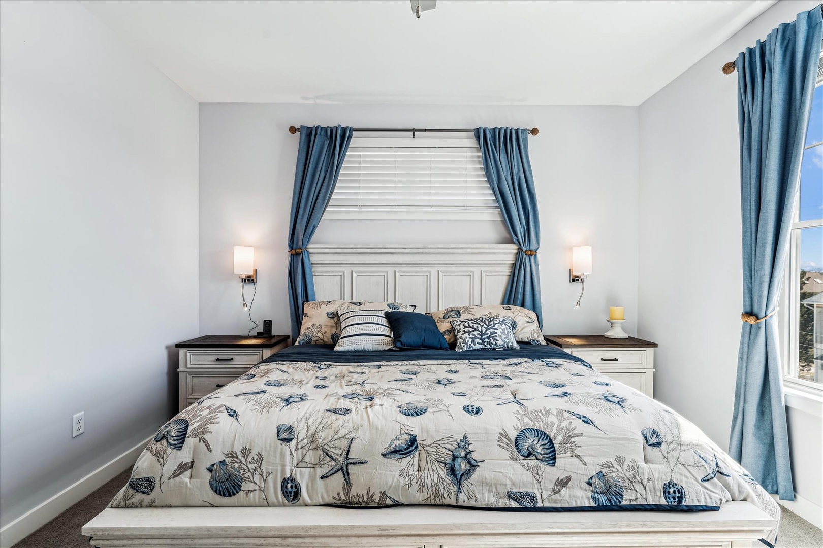 Drift off in this coastal-inspired bedroom with ocean-themed linens and elegant blue curtains framing your peaceful retreat.