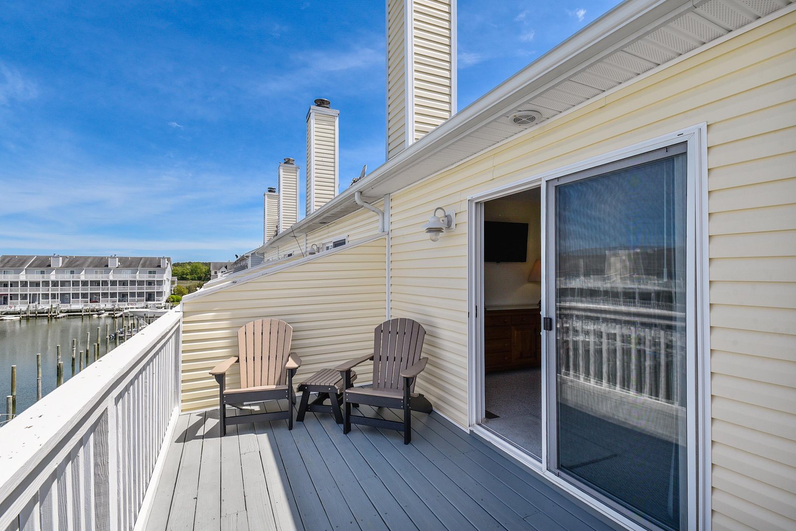 Step out onto your private waterfront deck, where two Adirondack chairs await. Breathe in the fresh air and watch the marina come to life under bright blue skies.