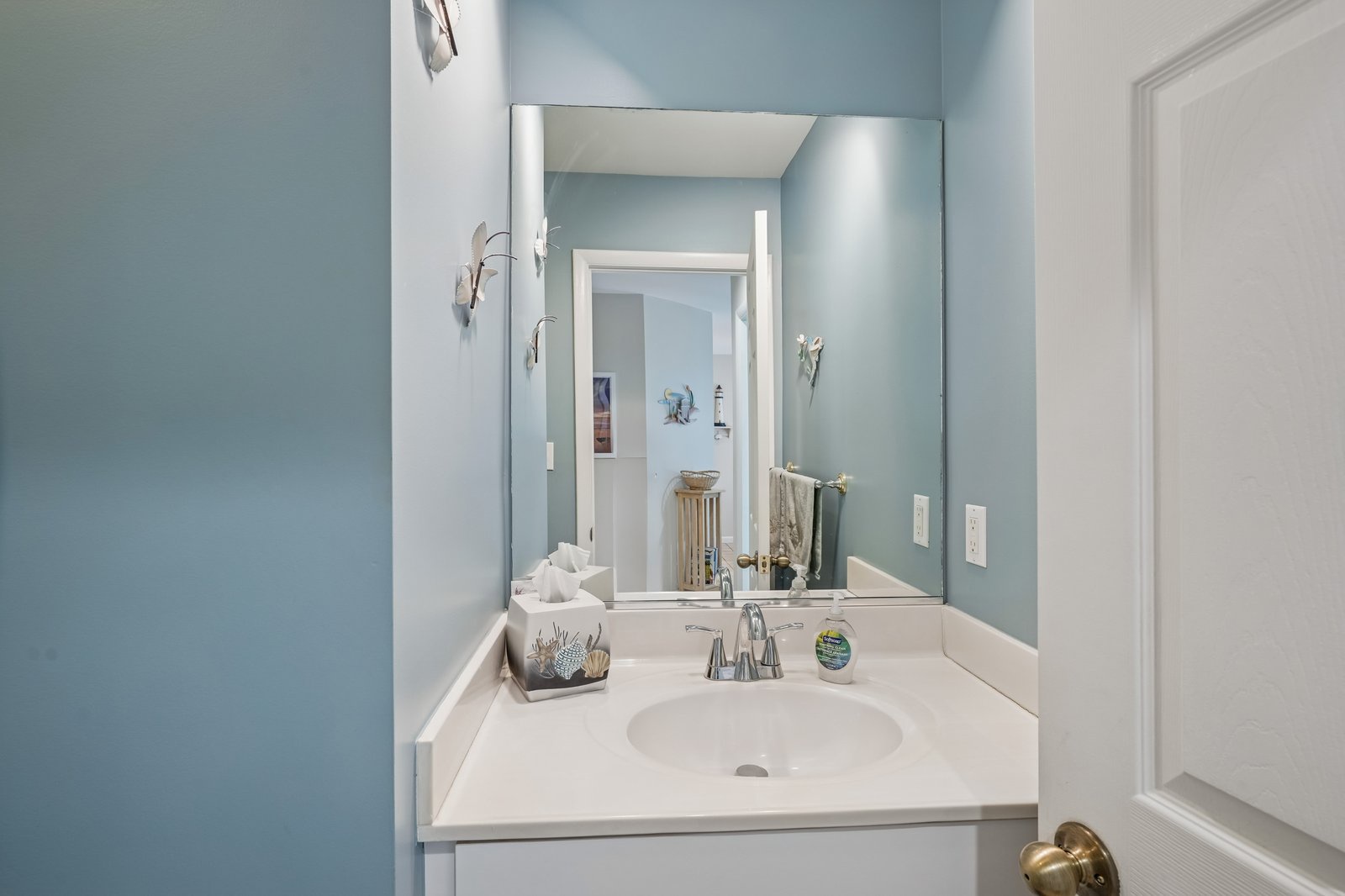 Step into your serene powder room featuring calming blue walls, pristine white vanity, and thoughtful coastal touches that create a peaceful retreat.