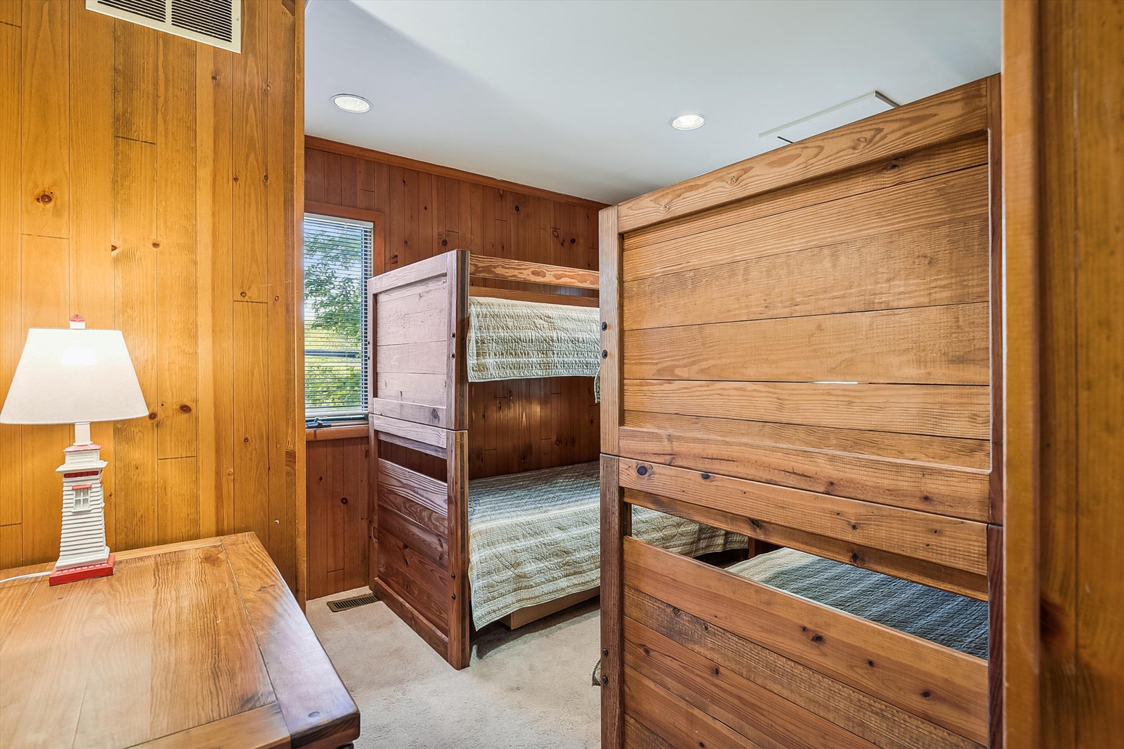 Your cozy bunk room features custom wood-crafted beds with nautical charm, perfect for the kids to unwind after a day of adventure. Warm lighting and natural wood create a snug retreat.