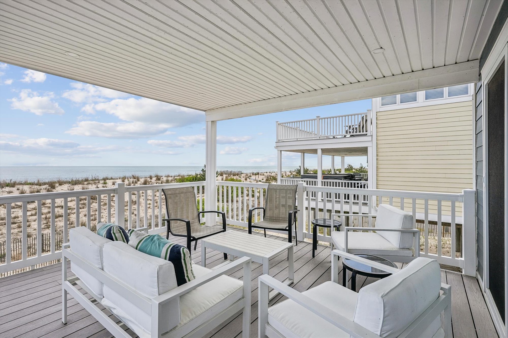 This spacious balcony offers a comfortable seating area with coastal views. Relax on cushioned outdoor furniture while enjoying the beach landscape and ocean breeze just steps away from your door.