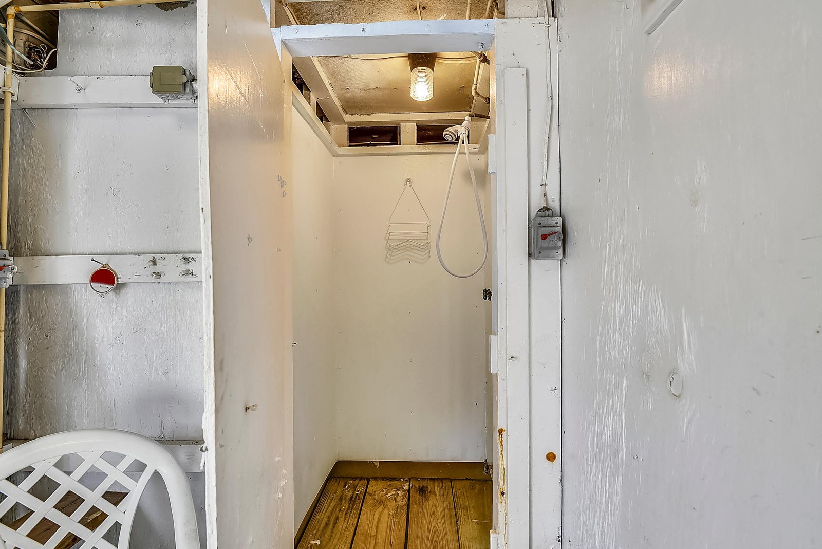 A simple, functional shower space with warm wood flooring and handheld shower fixture, providing the essentials for your stay.