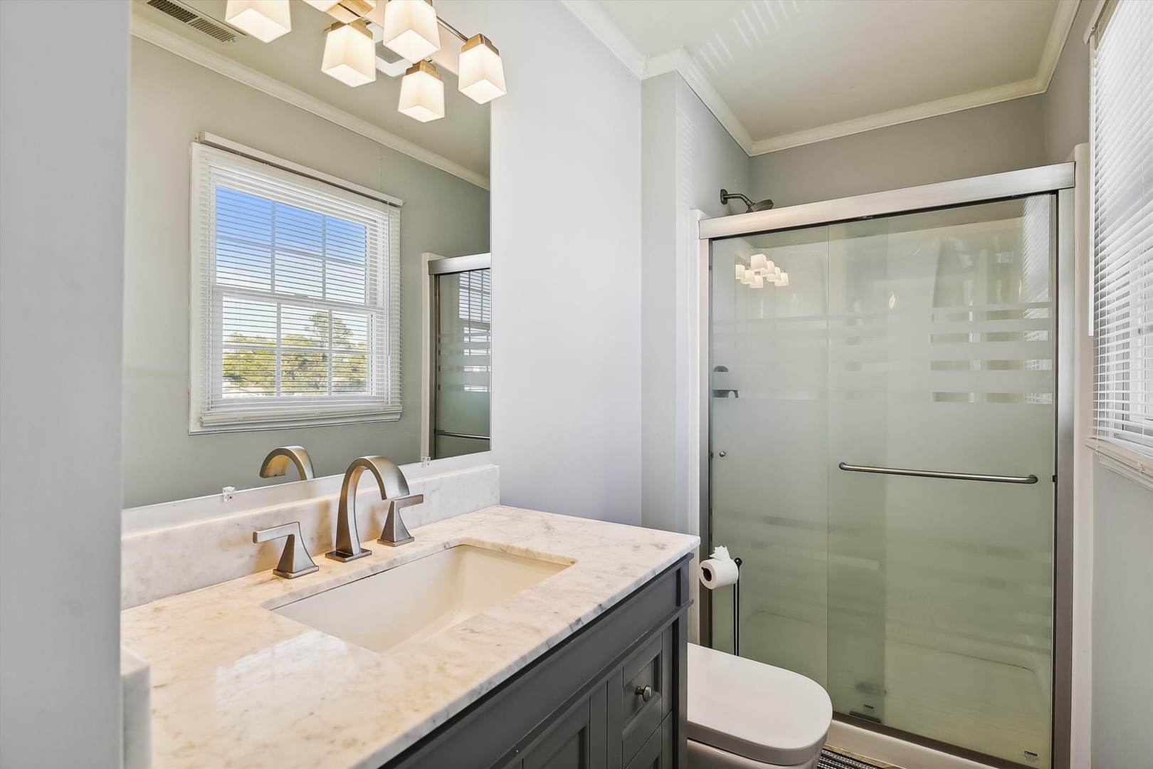 Unwind in your serene bathroom featuring a marble vanity, modern fixtures, and a spacious walk-in shower with sleek glass doors—your personal spa retreat.